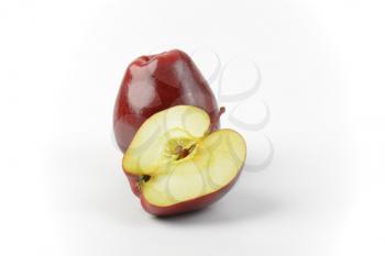 One and a half red apples on off-white background