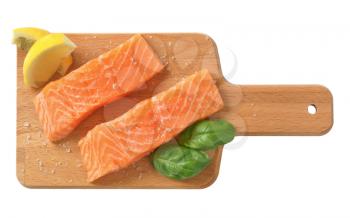 two salted salmon fillets on wooden cutting board