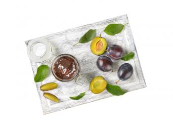 jar of plum jam and fresh plums on wooden cutting board
