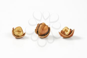three cracked hazelnuts on white background