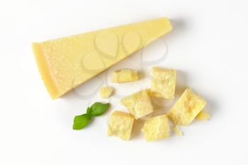 wedge and pieces of fresh parmesan cheese on white background
