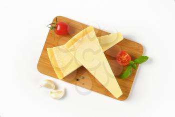 two wedges of parmesan cheese on wooden cutting board