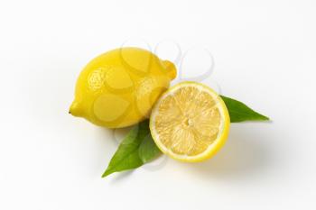 one and half lemon with leaves on white background