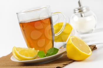 hot tea in glass mug, fresh lemon and sugar cellar