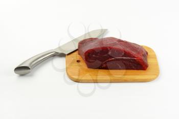 raw beef meat on wooden cutting board and chef's knife