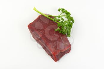 raw beef rump and fresh parsley on white background