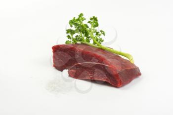 raw beef meat, salt and fresh parsley on white background