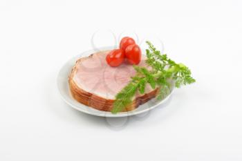 stack of ham slices, cherry tomatoes and dill on white plate