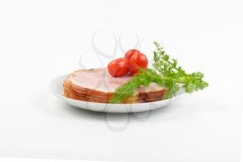 stack of ham slices, cherry tomatoes and dill on white plate