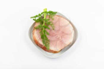 stack of ham slices and dill on white plate