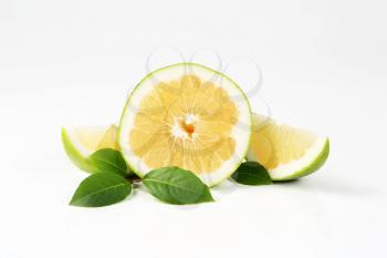 green grapefruit half and slices on white background