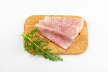 ham slices with dill rolled on wooden cutting board