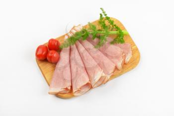 ham slices with dill an cherry tomatoes on wooden cutting board