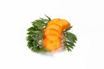 slices and leaves of fresh carrot on white background