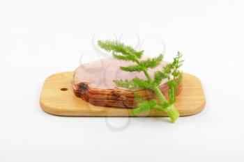 stack of ham slices and dill on wooden cutting board