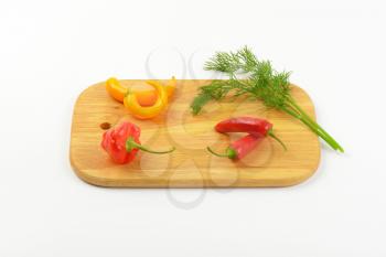 fresh chili peppers and dill on wooden cutting board