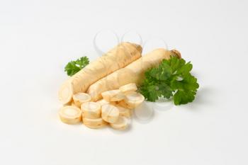 sliced parsley root with leaves on white background