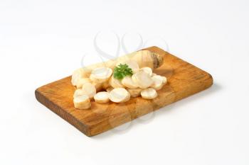 sliced parsley root on wooden cutting board