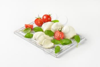 mozzarella, tomatoes and fresh basil leaves on cutting board