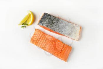Two raw salmon fillets and lemon on white background
