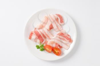 Thin slices of raw side pork on white plate