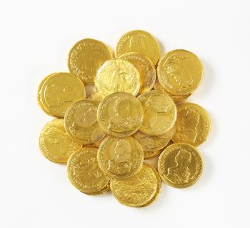 Heap of gold foiled chocolate coins on white background