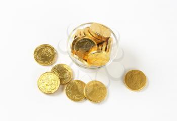 Gold foiled chocolate coins in glass bowl and next to it