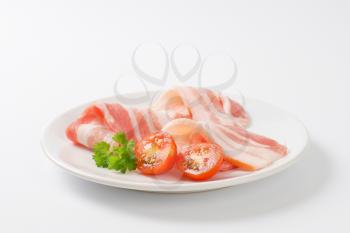 Thin slices of raw side pork on white plate
