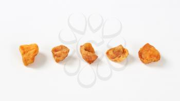 five pork greaves in a row on white background