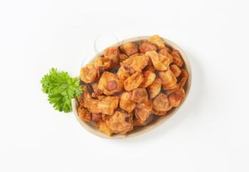 plate of salty pork greaves on white background