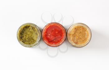 overhead view of assorted dipping sauces or pesto sauces in jars