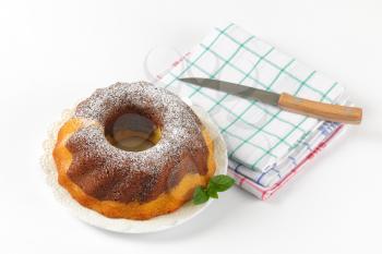 marble bundt cake, kitchen knife and checkered dish towels on white background