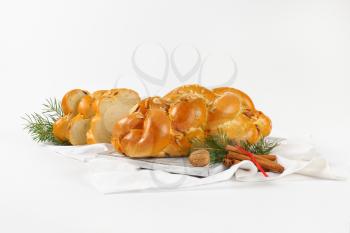 loaf of Christmas sweet braided bread on wooden cutting board and white napkin