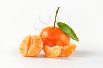 whole unpeeled tangerine with separated segments on white background