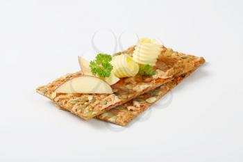 two butter curls and apple slices on pumpkin seed crackers