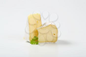 two slices of white rind cheese with parsley on white background