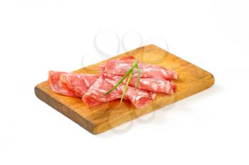 slices of dry salami arranged on wooden cutting board