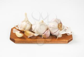 Fresh garlic bulbs and cloves on wooden cutting board