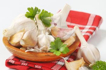 Fresh garlic bulbs and cloves on wooden plate