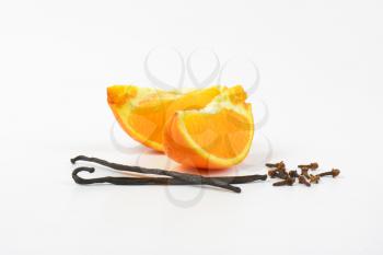 slices of orange, vanilla pods and cloves on white background