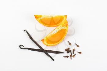 slices of orange, vanilla pods and cloves on white background