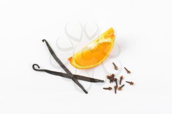 slice of orange, vanilla pods and cloves on white background
