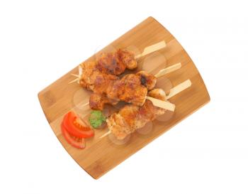 four spicy chicken skewers on wooden cutting board