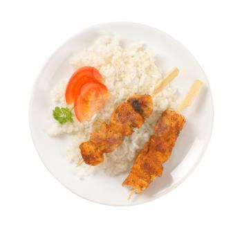 rice and grilled chicken skewers on white plate