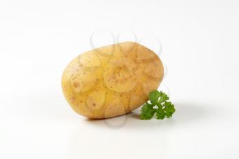 single raw potato and parsley on white background