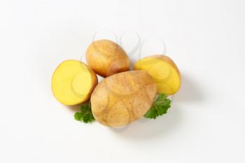 whole and halved raw potatoes and parsley on white background