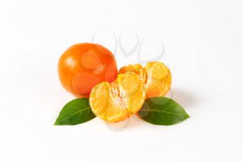 fresh tangerines peeled and unpeeled on white background