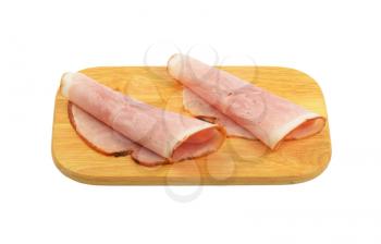 two ham slices rolled up on wooden cutting board