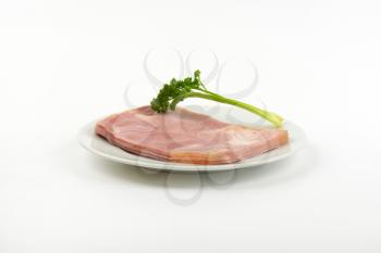 plate of fresh pork ham with parsley on white background