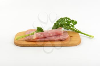 sliced pork ham with parsley on wooden cutting board